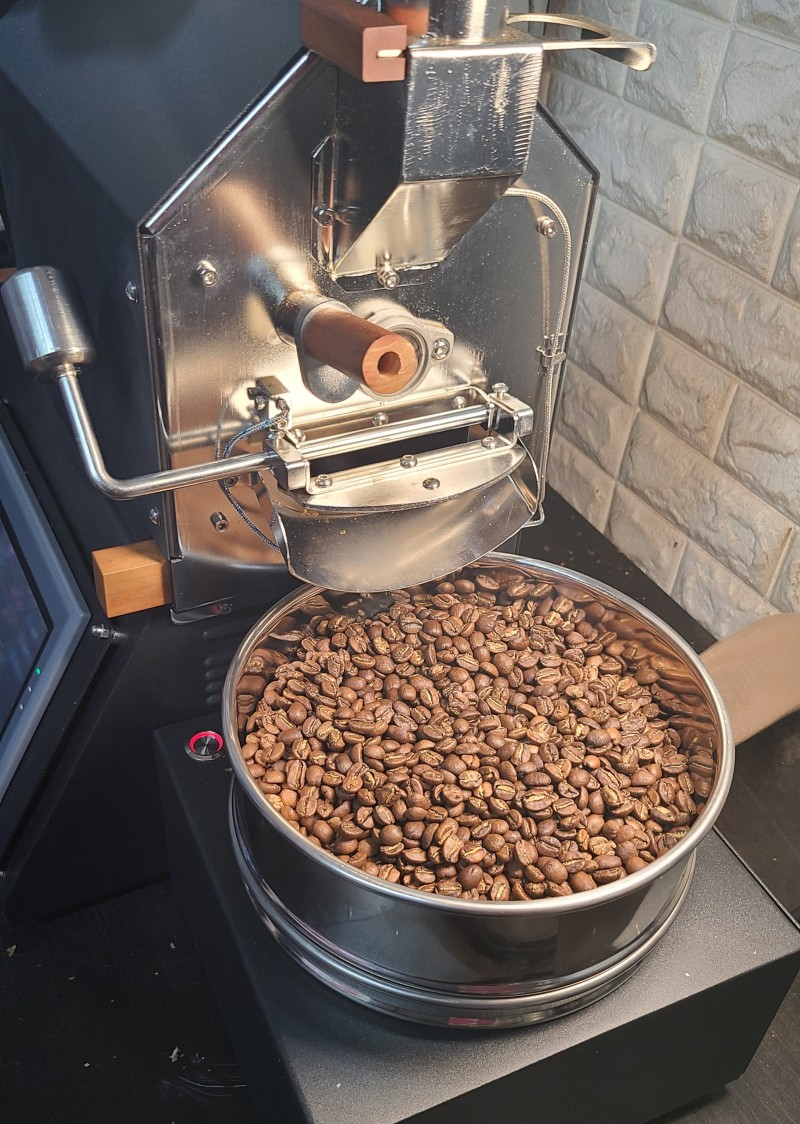 Coffee My Cup: Coffee roasting machine with a container of coffee beans on a stone wall background