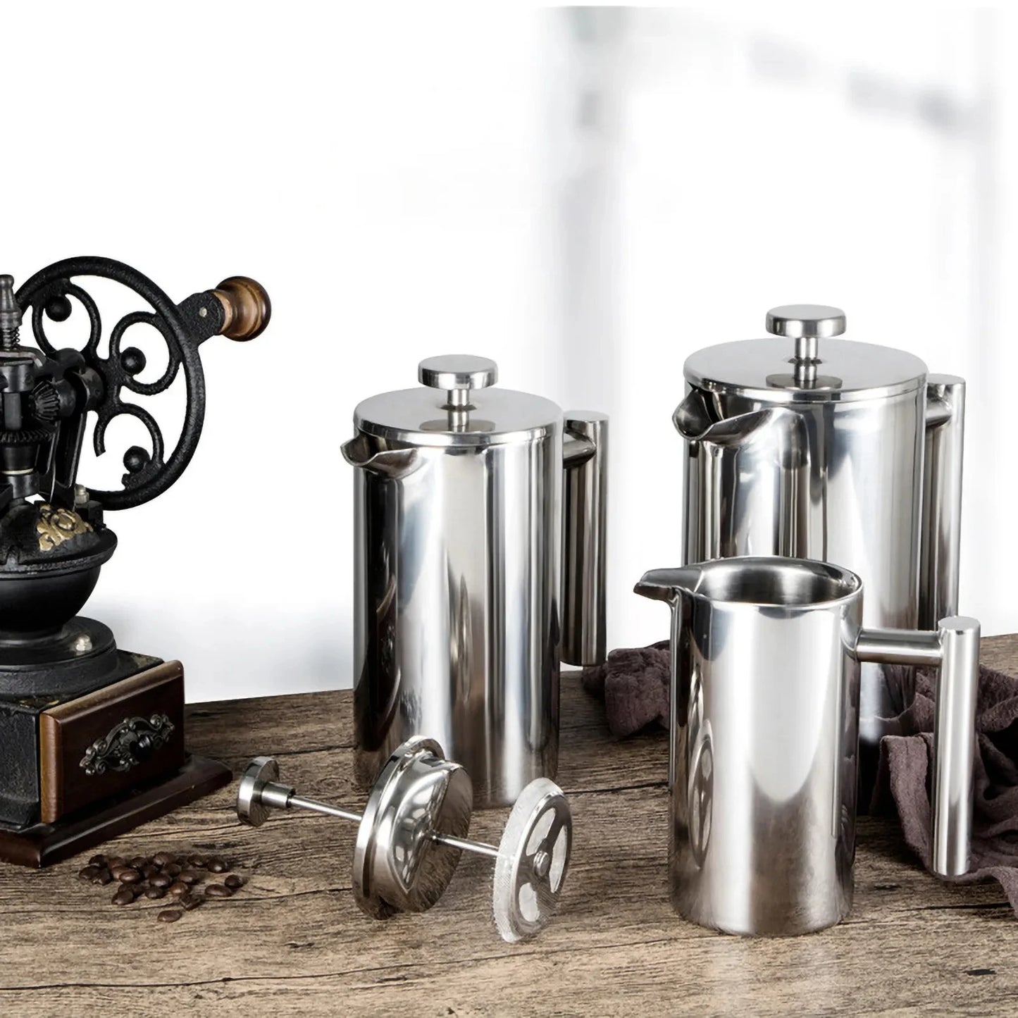Coffee My Cup: Set of stainless steel coffee pots and a vintage grinder on a wooden surface.