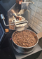 Coffee My Cup: Coffee roasting machine with a container of coffee beans on a stone wall background