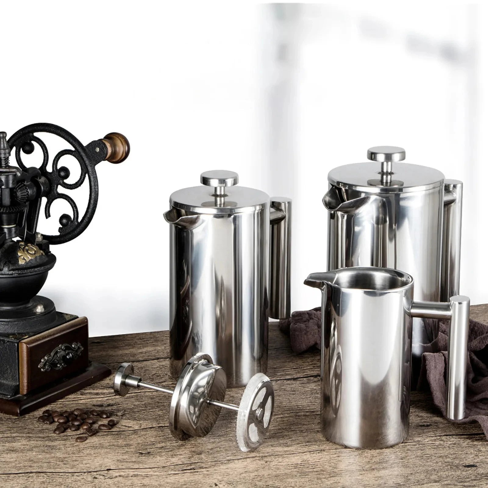 Coffee My Cup: Set of stainless steel coffee pots and a vintage grinder on a wooden surface.